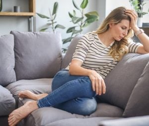 middle aged woman sitting on the couch (negative emotions)