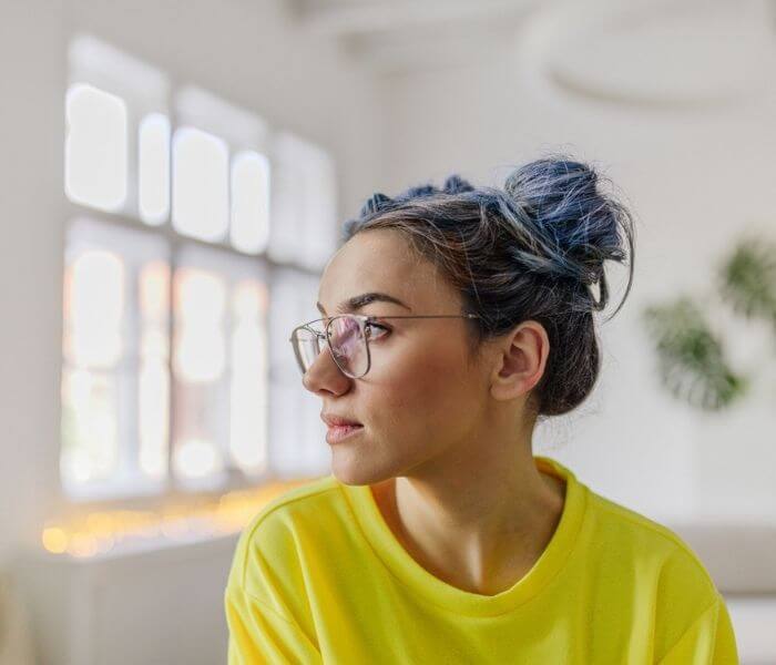 Young woman in yellow top staring out of the window